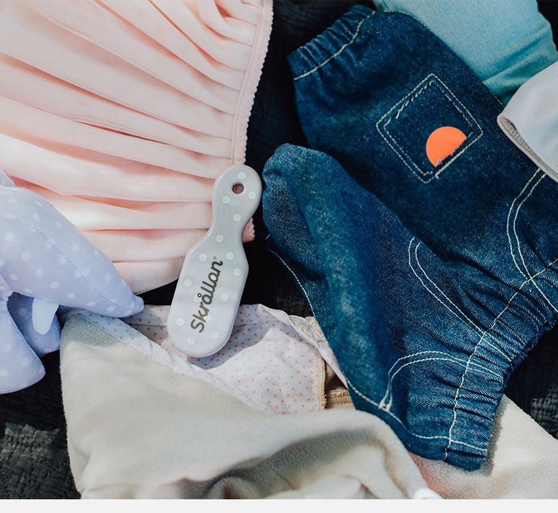 Et nærbillede af babytøj og tilbehør på et tæppe.