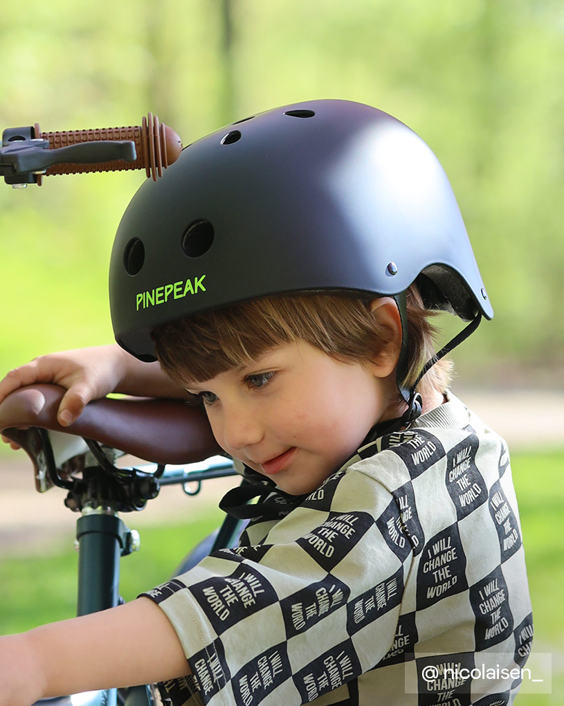 Barn med hjelm på cykel, iført trøje med teksten 'I will change the world'.