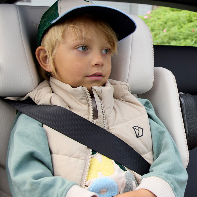 Glad barn med sikkerhedssele i autostol.