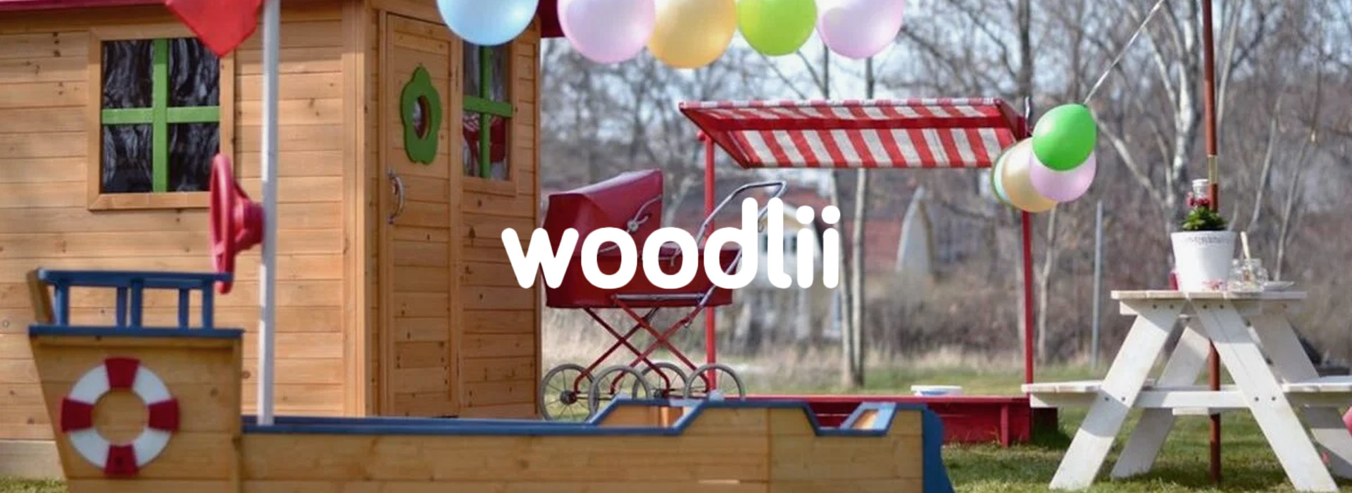 Legehus med balloner og træbænk i en have.