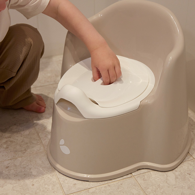 Barn på potte, der holder sin mors hånd.