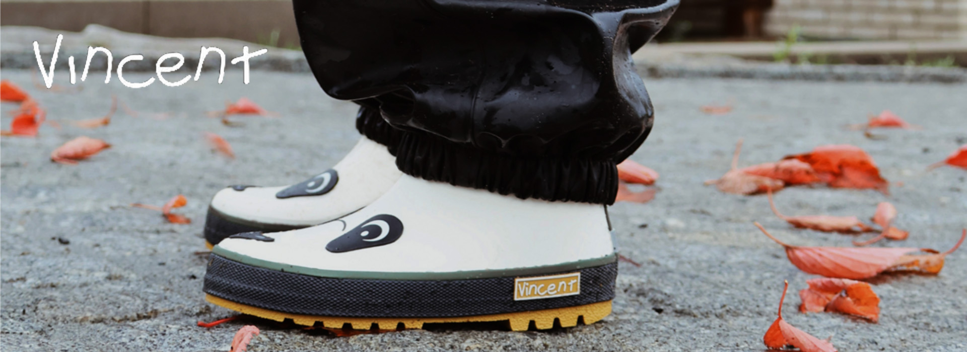 Børnestøvler med dyretryk på en grusvej med røde blade.