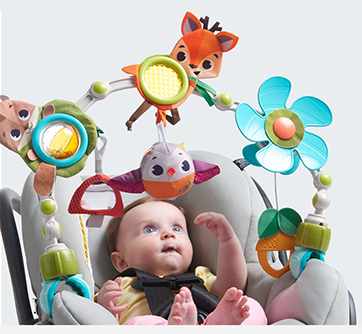 Baby i skråstol med legetøjshænger og farverige dyrefigurer.