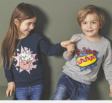 To smilende børn i trøjer med popcorn og hotdog tryk, peger legende.