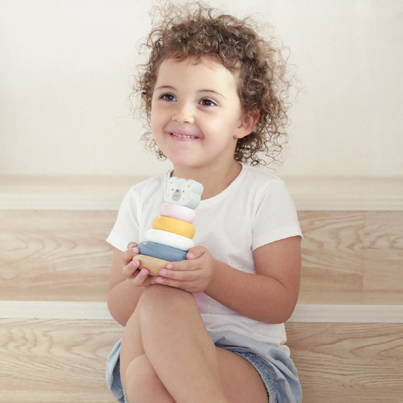 Barn leger med stablelegetøj af træ i pastelfarver.