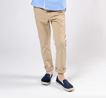 Person i beige bukser og blå sko, hvid baggrund.